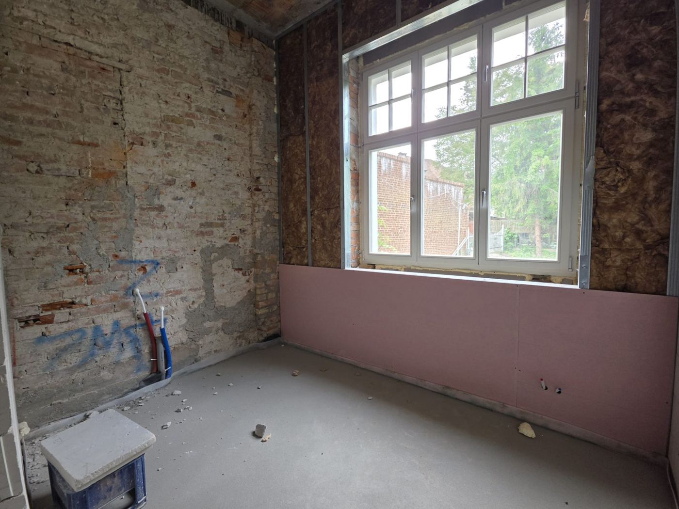 Nowe drewniane okno ze szprosami w ceglanej ścianie, czerwiec 2026